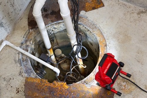 Open sump pit with exposed pump and emergency repair equipment in a residential basement